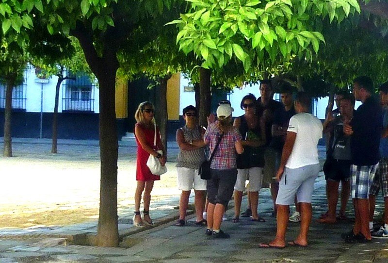 Un grupo de turistas atiende las explicaciones de una guía en Sevilla.