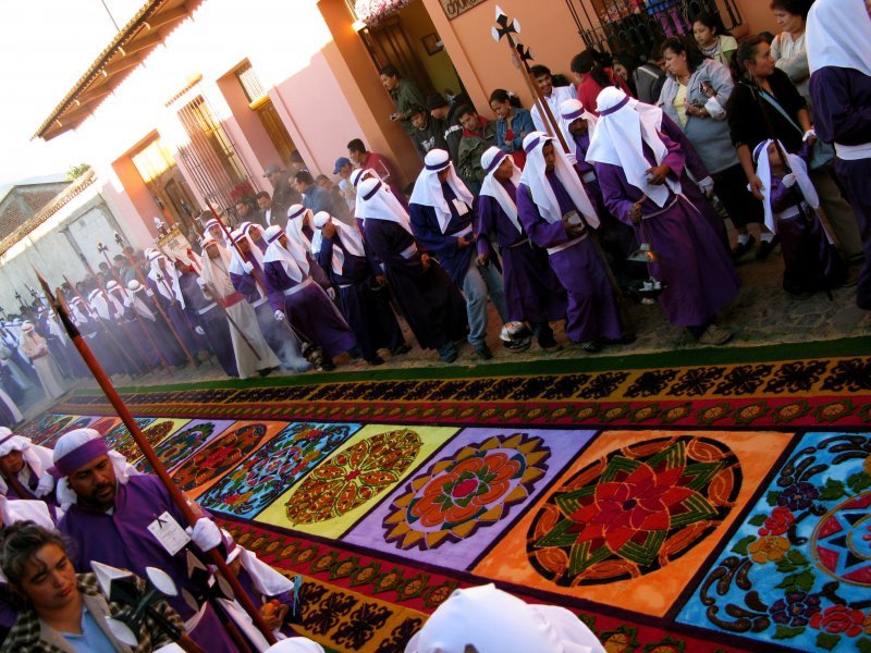 Los feligreses elaboran alfombras de serrin de colores.