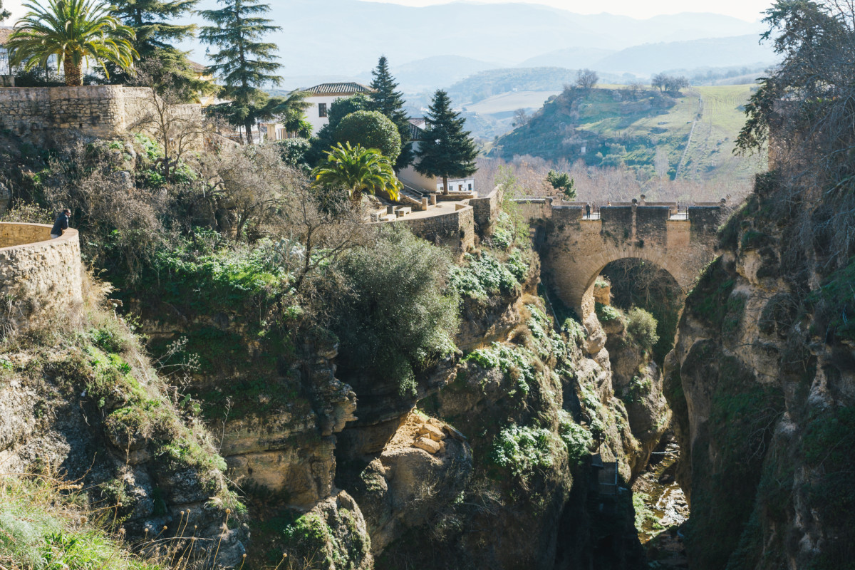 Turista contemplando la vista del puente viejo de Ronda y los Jardines de Cuenca 